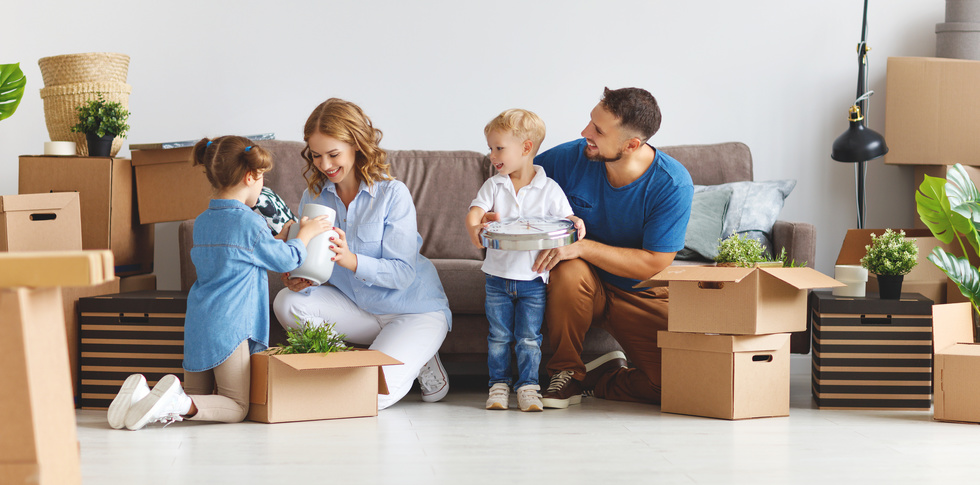 happy family mother father and children move to new apartment and unpack boxes