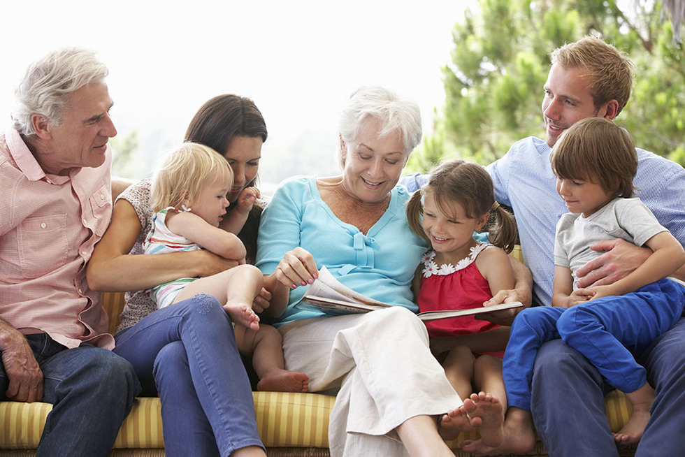Multi Generation Family Reading Book On Garden Seat